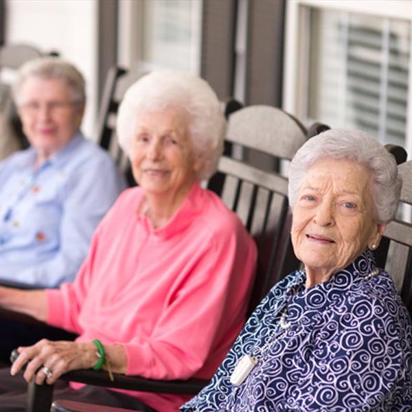 elderly women sitting on porch in rocking chairs