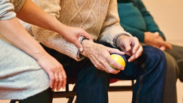 Image of elderly hands with ball and caretakers hands