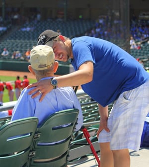 Younger man speaking to senior at a baseball game